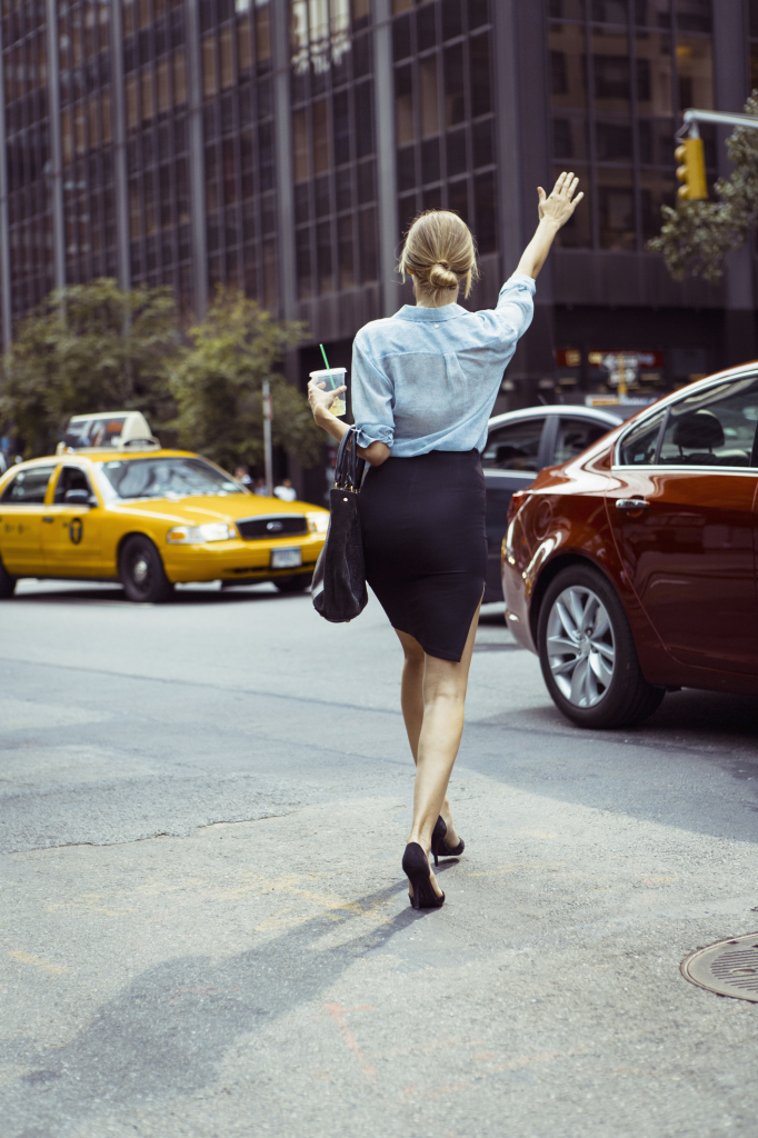 Caucasian woman hailing taxi в urban street